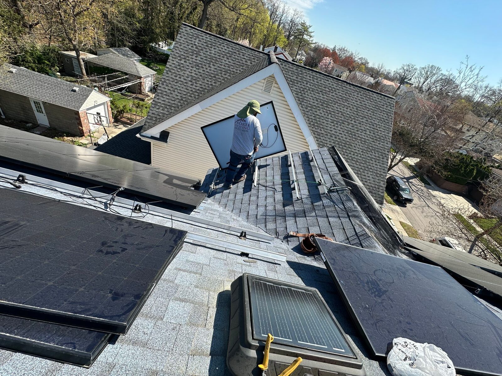 An installer working on a shingled roof
