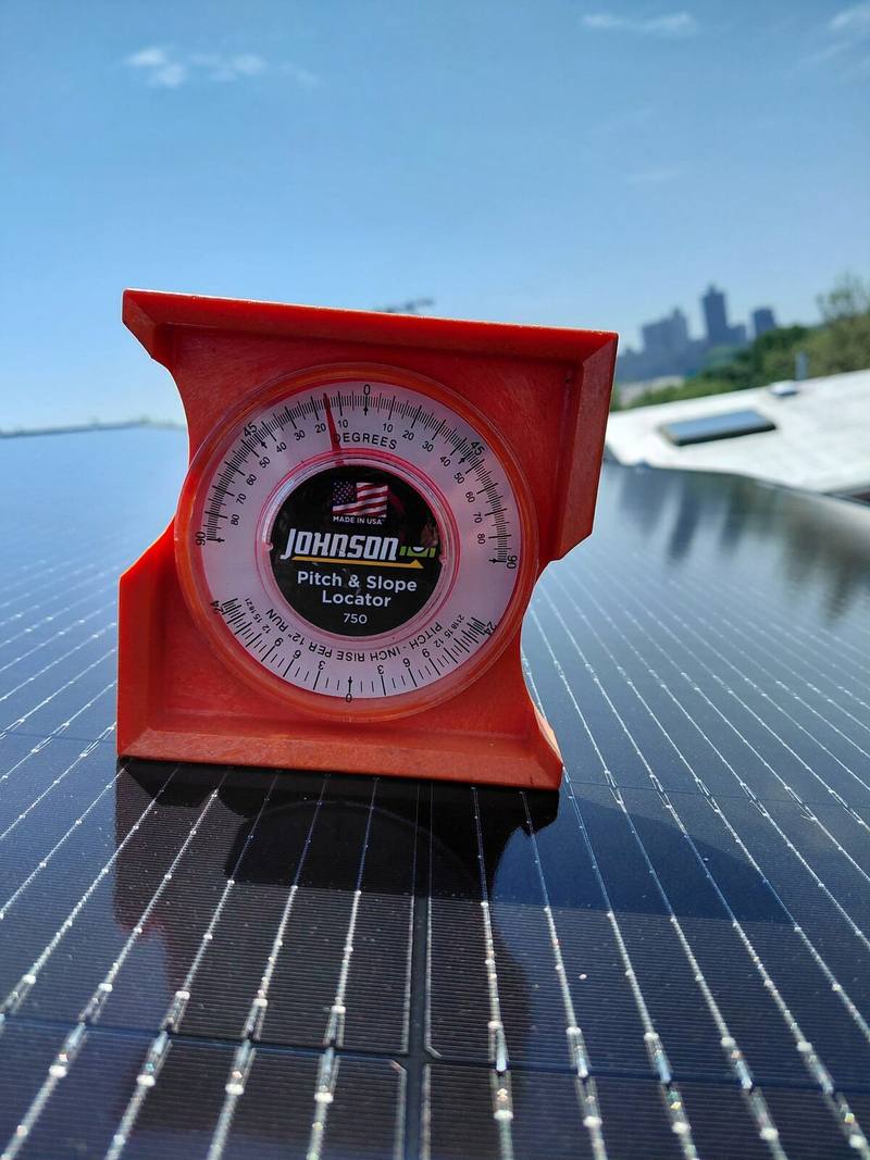 A pitch and slope gauge resting on a panel, skyline behind