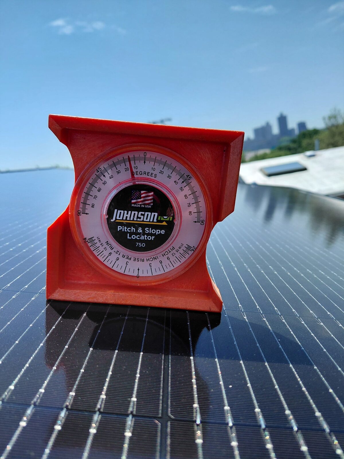 A pitch and slope gauge resting on a panel, skyline behind